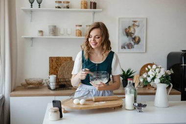 Beautiful girl cooks and looks at the recipe on the smartphone. High quality photo
