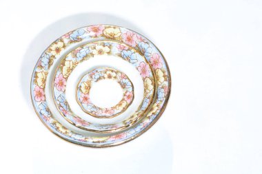 Beyaz yemek tabaklarını, çiçekli çay tabaklarını ve dalgalı üst görünümü izole et.