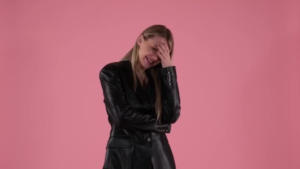 Hübsche Frau lacht zu Tränen auf rosa Hintergrund — Stockvideo