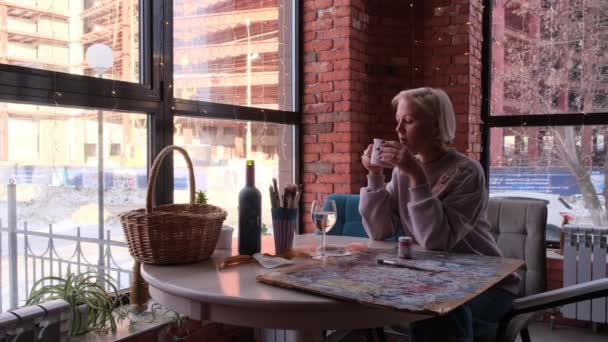 El artista bebe café sentado junto a la ventana y sueña — Vídeos de Stock