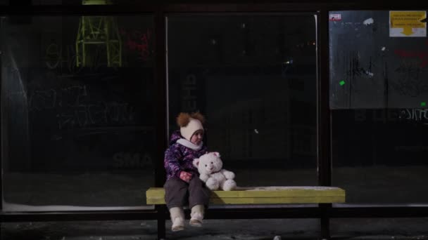 Dziewczyna pieszcząca misia na przystanku autobusowym — Wideo stockowe