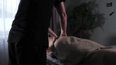 Sırtına masaj yapan siyah tişörtlü bir masör.