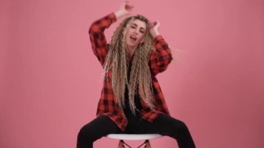 Kız sandalyede otururken dans ediyor