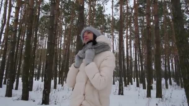Dziewczyna w zimowym lesie spogląda w niebo — Wideo stockowe