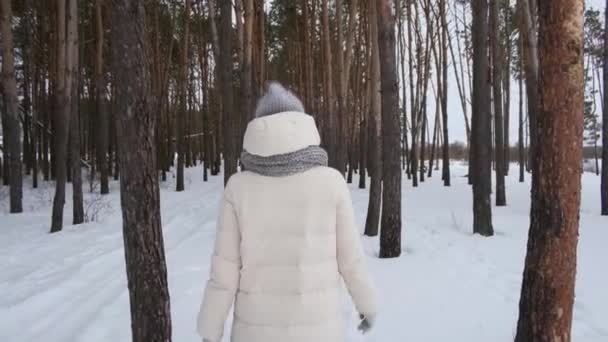 Egy kislány fehér dzsekiben sétál az erdőben. — Stock videók