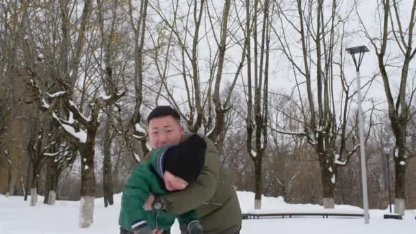 Egy fiatal apa játszik a kisfiával a téli parkban.. — Stock videók