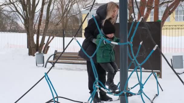 Mama pomaga małemu synowi wspiąć się na liny — Wideo stockowe