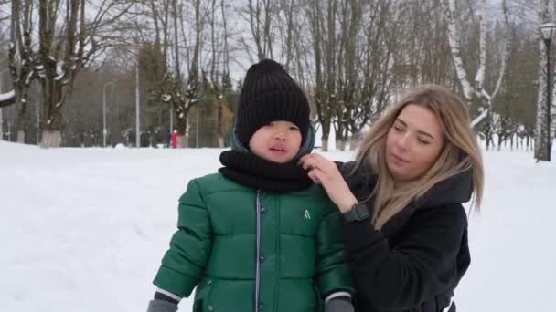 Moeder rechte de hoed en sjaal van haar kleine zoon — Stockvideo