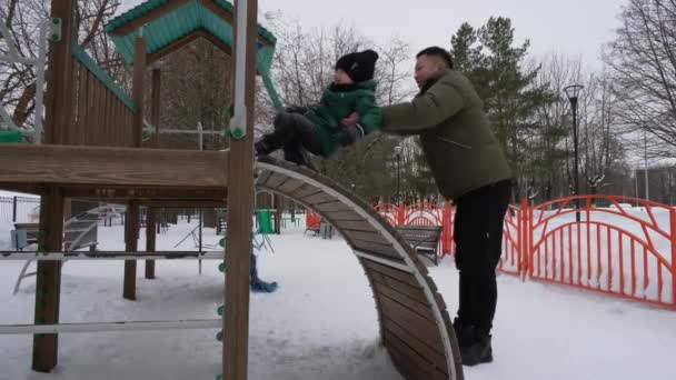Dad helps son to climb a childrens slide — Stock Video