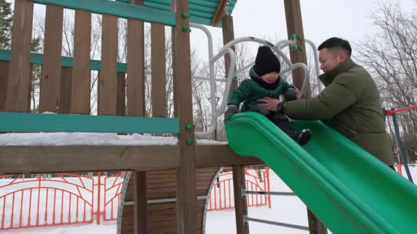 Far hjälper lille son att glida nerför kullen — Stockvideo