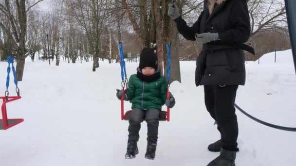Little asian boy swinging on a swing in winter park — Stock Video