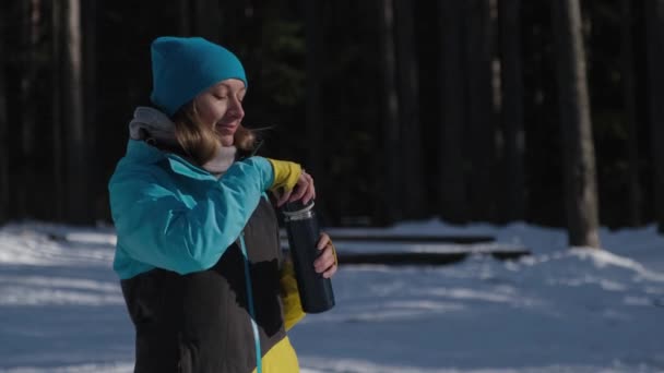 Una ragazza nella foresta si riscalda con tè caldo da un thermos — Video Stock