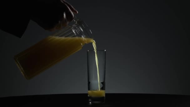O suco de laranja é derramado em um copo em um fundo neutro — Vídeo de Stock