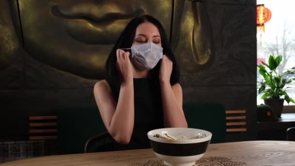 Brunette riisuu naamionsa ravintolassa syömään herkullista ruokaa — kuvapankkivideo
