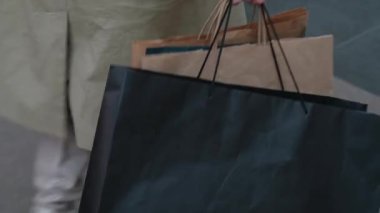 Kız alışveriş merkezinde alışveriş torbaları taşıyor.