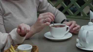 Kız bir fincan çayın içinde şeker karıştırıyor.