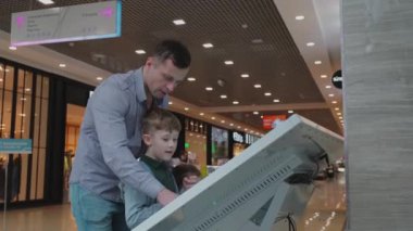 Çocuklu bir adam alışveriş merkezinin interaktif haritasını inceliyor..