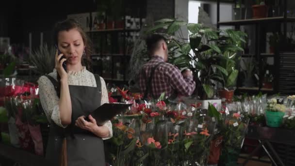 Дівчина флорист розмовляє по телефону — стокове відео