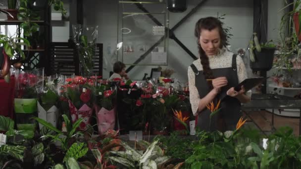 The girl writes down the state of the flowers — Stock Video