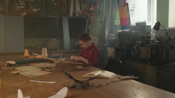 Мальчик украшает модель своего самолета наклейками — стоковое видео