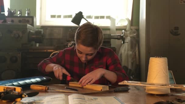 Un adolescente trabaja con un cuchillo de papelería y un archivo — Vídeos de Stock