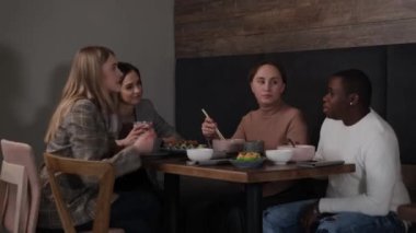 Asyalı bir kafede yemek yiyen ırklar arası bir arkadaş grubu.