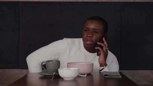Black guy talking on the phone in a cafe — Stock Video