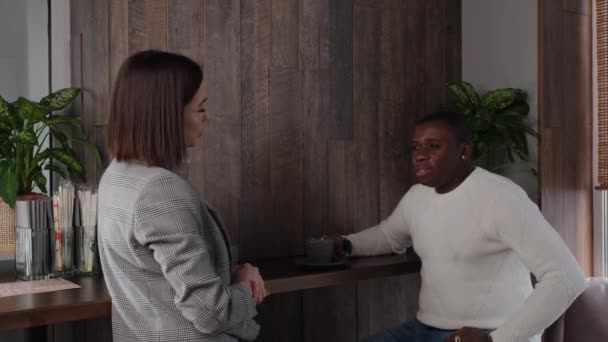 Un chico negro y una chica blanca charlan en un café — Vídeos de Stock