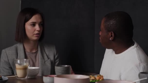 Beyaz kız ve siyah adam bir kafede tartışıyor. — Stok video