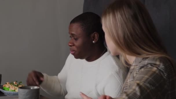 Eine Blondine und ein Schwarzer unterhalten sich in einem Café — Stockvideo