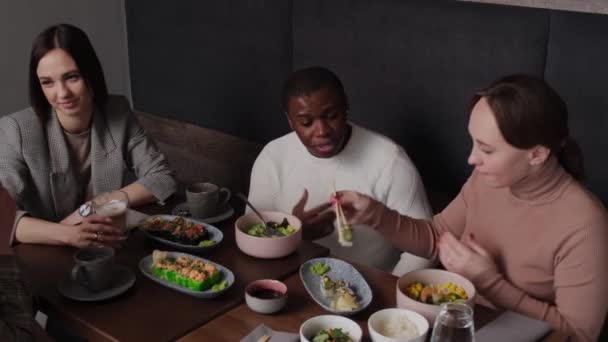 Meisje voedt Afro-Amerikaanse man sushi — Stockvideo