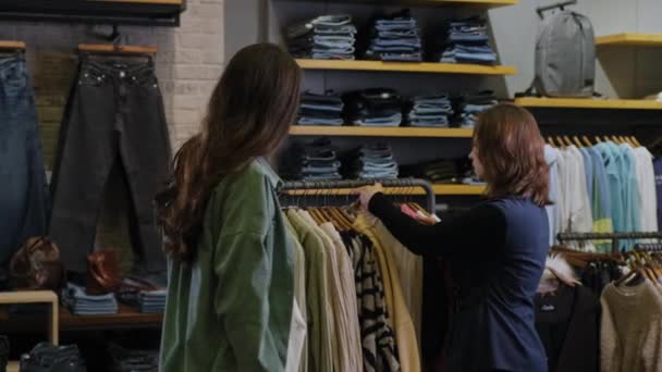 Sprzedawca odzieży konsultujący się z młodą klientką — Wideo stockowe