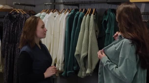 Βοηθός πωλήσεων βοηθώντας μια γυναίκα να επιλέξει ρούχα — Αρχείο Βίντεο