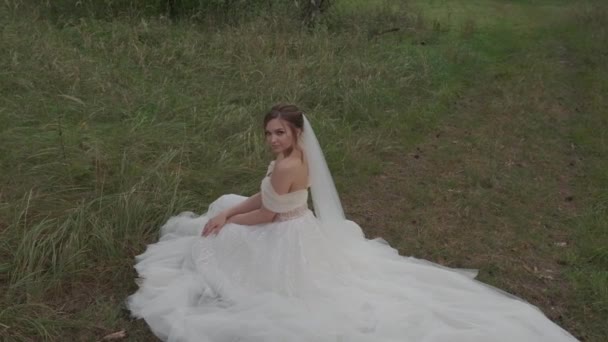 Menyasszony ruhában ül a füvön. — Stock videók