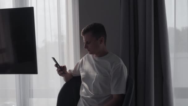 Ženich sedí s telefonem v hotelovém pokoji — Stock video