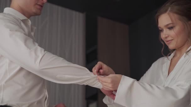 Bruden hjälper brudgummen sätta på manschettknappar — Stockvideo