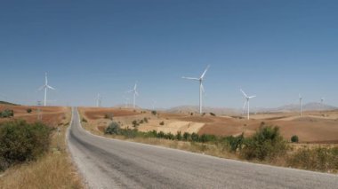 Dağlarda temiz enerji üretimi için yel değirmenleri tarlasından geçen yol