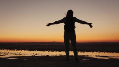 Gün batımından sonra elini kaldıran bir adamın silueti.