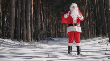 Gülümseyen Noel Baba el sallayarak selamlıyor.