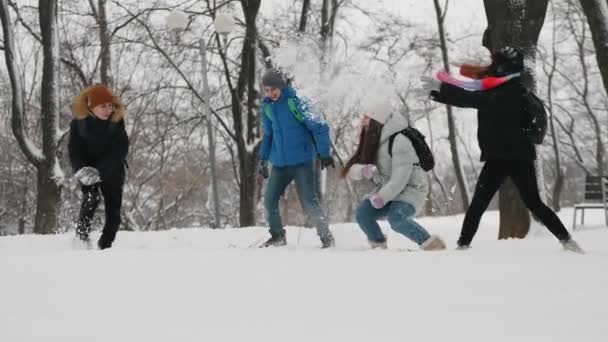 Crianças se divertem jogando neve umas nas outras no parque da cidade — Vídeo de Stock