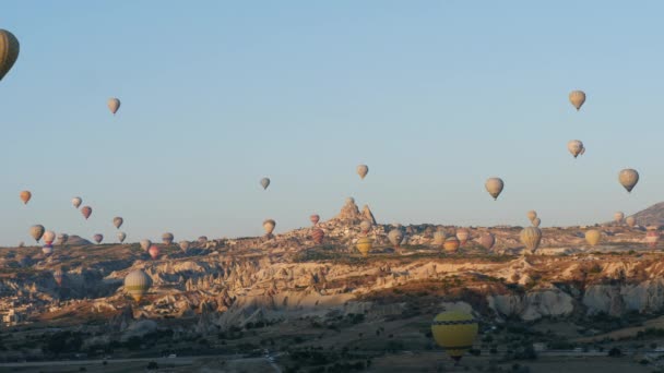 Cappadocia, Turecko, cca léto 2021: Časová prodleva pestrobarevných horkovzdušných balónů přeletět nad údolím a městem časně ráno — Stock video