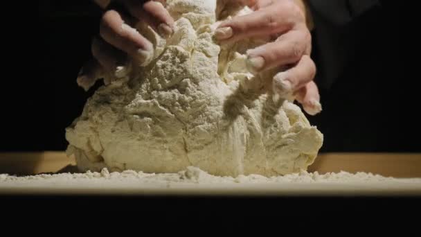 烘培者的双手揉碎在黑色背景下的面团 — 图库视频影像