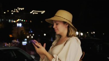 Bir kadının, gece yarısı bir caddenin ortasında akıllı telefon kullanırken çekilmiş bir fotoğrafı.