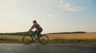Kırsalda bisiklet süren şişman genç bir kadın.