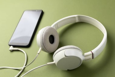 Kulaklığı yeşil arka planda olan akıllı telefon, kulaklıklı ya da sesli kitapları dinleyin.