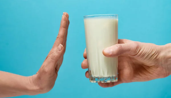 手は青の背景にミルクのガラスを拒否します 不寛容という概念を — ストック写真