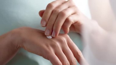 A woman applies a cosmetic hand skin care cream.