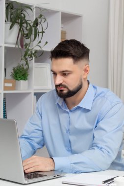 Yakışıklı adam, internetteki modern bir iç mekanda dizüstü bilgisayarda çalışıyor..