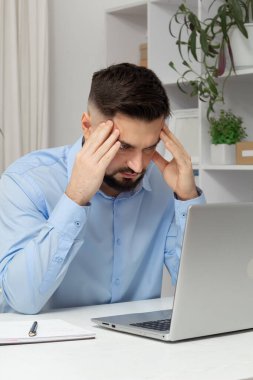 Dizüstü bilgisayarla çalışan yorgun bir iş adamının başındaki ağrı..