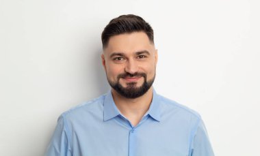 Beyaz arka planda sakallı, tişörtlü mutlu bir adamın portresi..